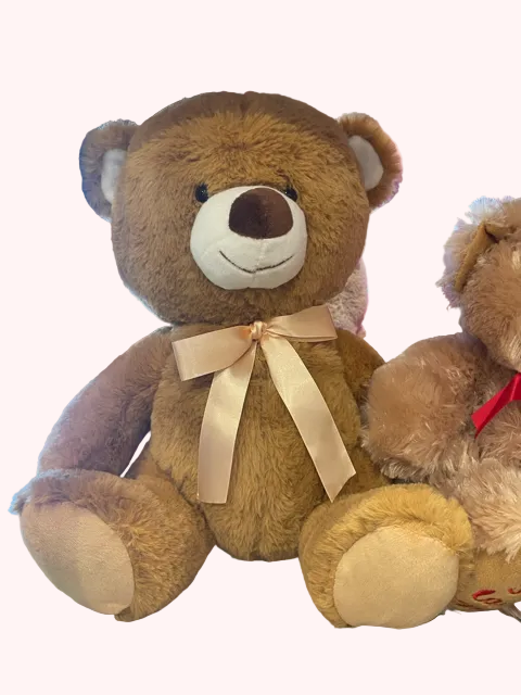A plush brown teddy bear with a beige bow ribbon around its neck, sitting upright.