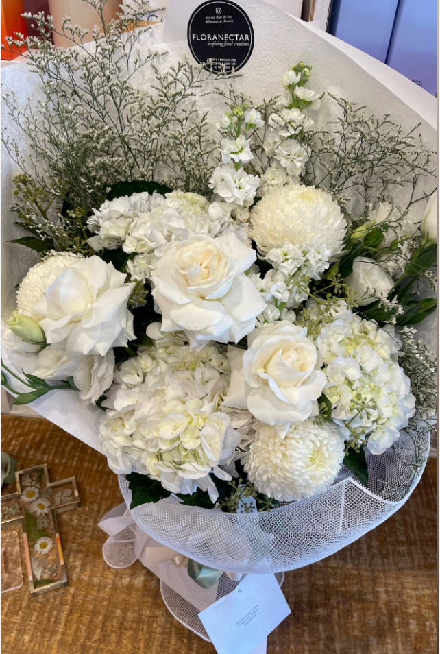 Bouquet of white flowers with a visible brand label on a textured surface.