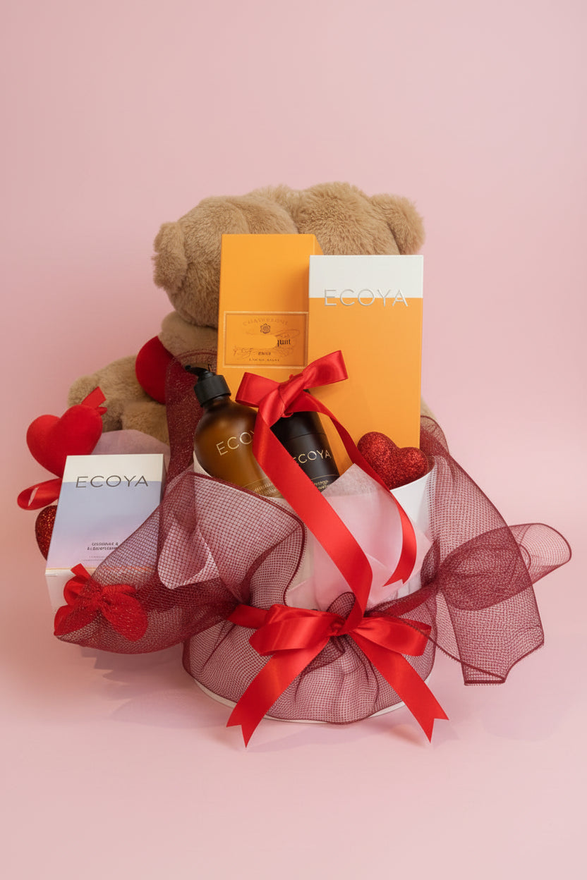 Gift basket with teddy bear, EGOYA products, and red ribbons on a table.